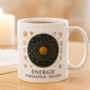 Mug astrologique blanc Orakya avec design doré “Énergie Harmonie Destin” posé sur une table en bois clair, à côté d’un livre et d’une bougie allumée – tasse en céramique brillante, ambiance zen, lumière naturelle du matin.